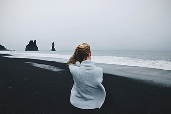 Woman gazing at Reynisfjara Beach's dramatic sea stacks, Iceland. HD wallpaper