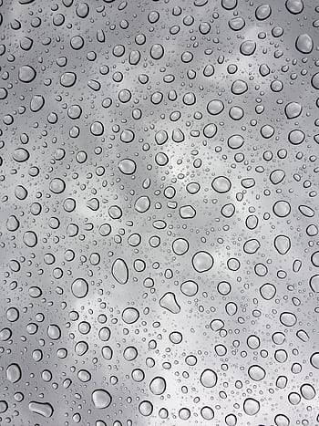 Macro shot capturing raindrops on a glass surface highlighting the purity and clarity of water. HD phone wallpaper