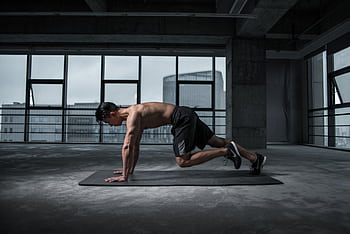 Fit man doing mountain climbers exercise inside a modern gym HD wallpaper
