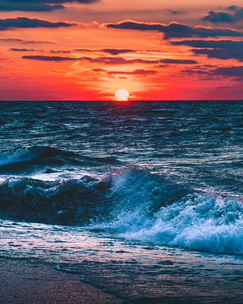 A stunning sunset over a tranquil ocean with dramatic clouds and gentle waves. HD phone wallpaper