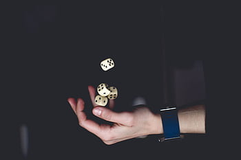 A close-up of a hand tossing several dice against a dark background, symbolizing chance and luck. HD wallpaper