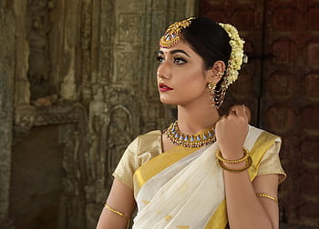 Beautiful Indian woman in traditional saree, adorned with exquisite jewelry, set against historic architecture. HD wallpaper