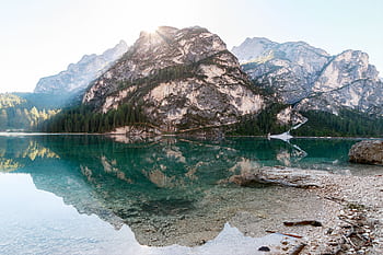 Pristine mountain lake with stunning reflections, surrounded by rugged peaks and lush forests. HD wallpaper