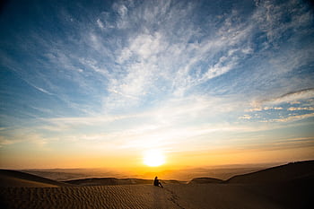 A stunning sunset over desert dunes in Paracas, Peru, with a solitary silhouette capturing tranquility. HD wallpaper