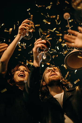 Group of friends enjoying New Year's Eve party with confetti and drinks. HD phone wallpaper