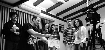 A group of adults collaborate on a filmmaking project, seen holding a clapperboard indoors. HD wallpaper