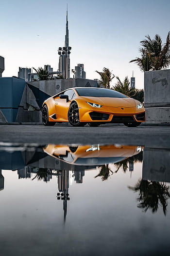 Striking of a luxury Lamborghini with its reflection in an urban cityscape, showcasing elegance and speed. HD phone wallpaper