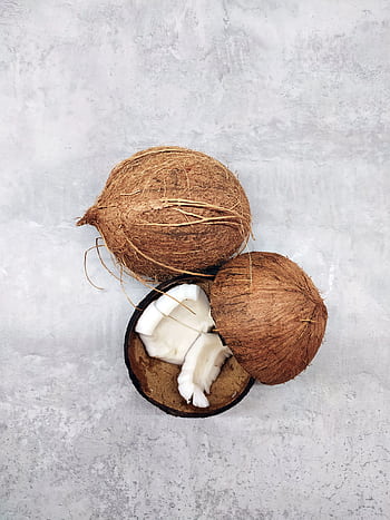Fresh whole and sliced coconuts on a textured gray background, captured from above. HD phone wallpaper