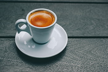 A stylish espresso in a porcelain cup on a wooden table, perfect for coffee lovers. HD wallpaper