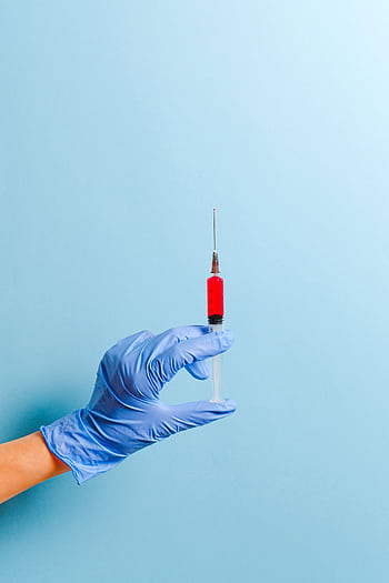 A gloved hand holds a syringe with red liquid, set against a blue background. HD phone wallpaper