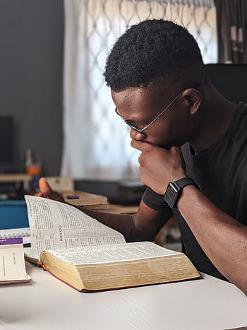 Young man deeply engaged in reading a book at home, fostering knowledge and wisdom. HD phone wallpaper