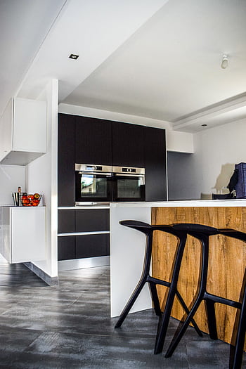 A contemporary kitchen featuring sleek cabinetry and elegant bar stools in a minimalist design. HD phone wallpaper