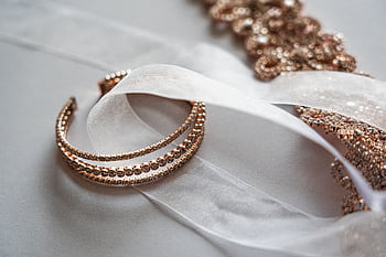 Close-up of luxurious rose gold jewelry on a sheer satin fabric, perfect for bridal occasions. HD wallpaper