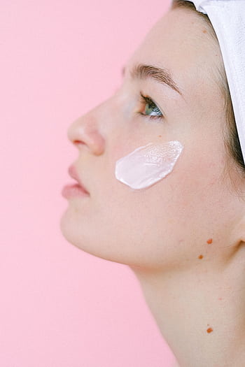 A serene portrait of a woman with facial cream against a pink background. HD phone wallpaper