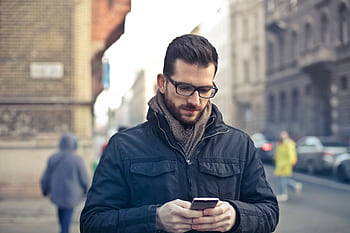 Adult man with glasses using a smart on a city street in Budapest, Hungary. HD wallpaper