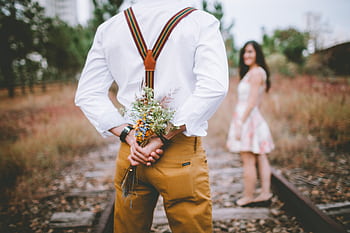 A romantic surprise proposal with a bouquet on an abandoned railway track. HD wallpaper