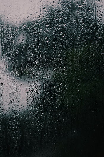 A dark and textured close-up of rain on a glass surface, capturing reflections and moodiness. HD phone wallpaper