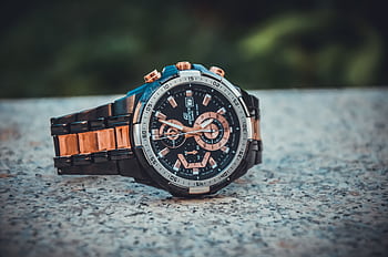 Close-up of an elegant wristwatch with a metal band, highlighting its intricate design and timekeeping features. HD wallpaper
