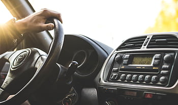 Close-up of a hand on a steering wheel inside a car, dashboard visible. HD wallpaper