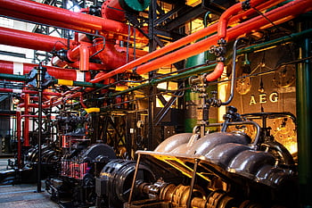 Vibrant industrial machinery with red pipes and complex equipment in a factory. HD wallpaper