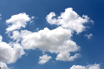 Fluffy white clouds float against a vibrant blue sky, symbolizing tranquility and dom. HD wallpaper