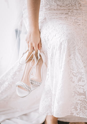 Close-up of woman holding bridal shoes wearing elegant white dress. HD phone wallpaper