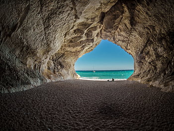 Discover a peaceful beach scene framed by a natural cave formation, perfect for relaxation. HD wallpaper