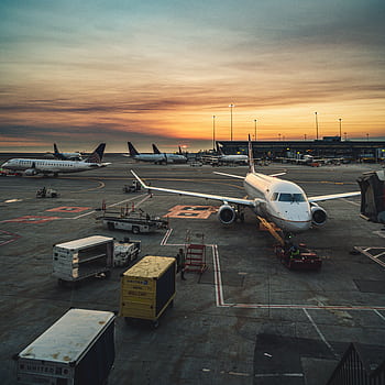 Airplanes parked at a busy airport terminal during sunset, showcasing aviation and travel. HD phone wallpaper