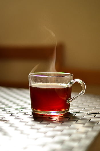 A steaming glass of tea adds warmth to an indoor setting, captured in a modern style. HD phone wallpaper