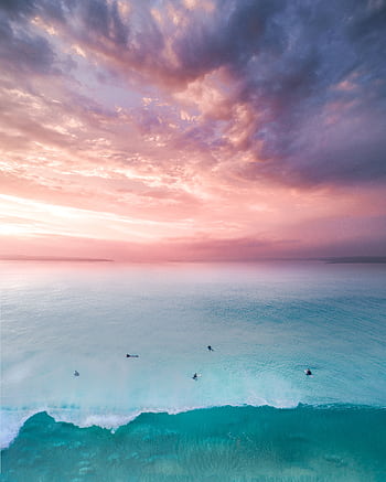 Dramatic sunset over Maroubra Beach with pink sky and turquoise ocean. Surfers enjoy the serene view. HD phone wallpaper