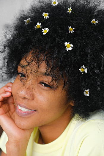 A cheerful woman with flowers in her curly hair, exuding natural beauty and joy. HD phone wallpaper