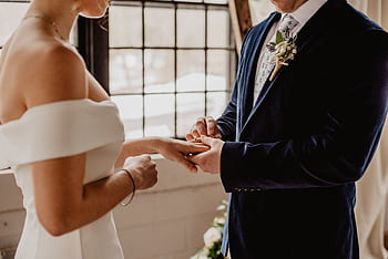Couple exchanging rings during an intimate indoor wedding ceremony, symbolizing love and unity. HD wallpaper