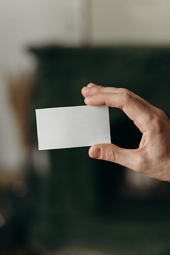 Close-up of a hand holding a blank white card with blurred background, perfect for business presentations and mockups. HD phone wallpaper
