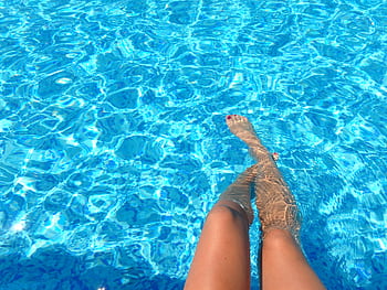 A person relaxes in a swimming pool with clear blue water, capturing summer vibes. HD wallpaper