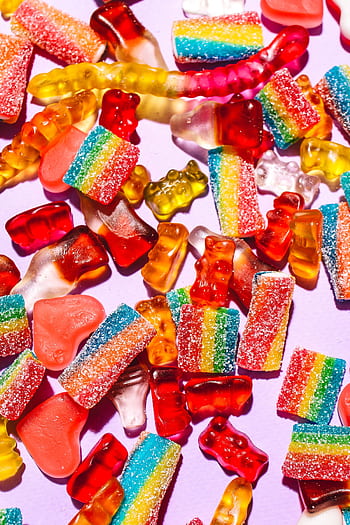 A colorful array of gummy candies including bears and worms on a purple backdrop. HD phone wallpaper