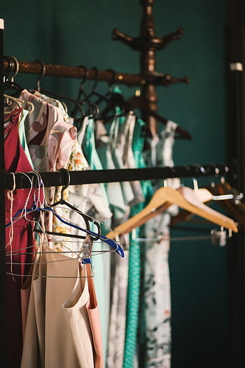 A collection of elegant dresses hanging on a clothes rack in a stylish wardrobe setup. HD phone wallpaper