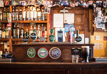 A warm, inviting pub with various beer brands on tap, perfect for social gatherings. HD wallpaper