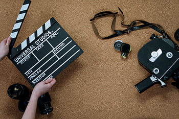 Top view of vintage film camera and clapperboard on cork background, evoking old cinema vibes. HD wallpaper