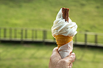 Enjoying a soft vanilla ice cream cone with a chocolate flake on a sunny day. HD wallpaper