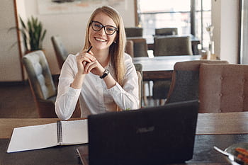 Young businesswoman wearing glasses works at a café with a laptop and notebook. HD wallpaper