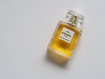 Elegant eau de parfum bottle with luxurious golden liquid on a minimalistic white background. HD wallpaper