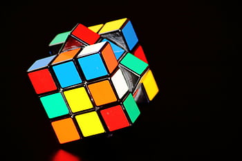 A close-up of a colorful Rubik's Cube puzzle, showcasing concentration and play. HD wallpaper