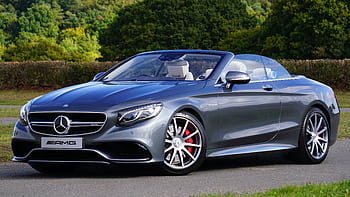 A sleek luxury convertible car parked outdoors with lush greenery. HD wallpaper