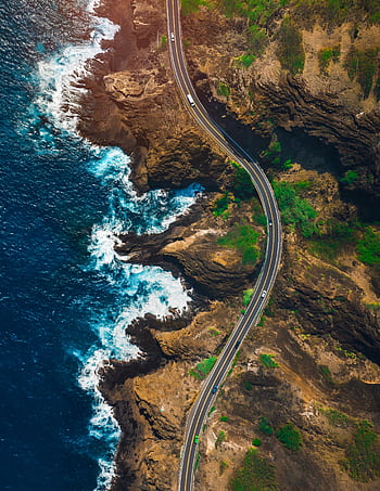 Stunning aerial shot of a winding coastal road in Hawaii with vibrant ocean waves. HD phone wallpaper