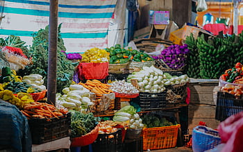 Vibrant array of fresh fruits and vegetables displayed at a bustling market stall. HD wallpaper