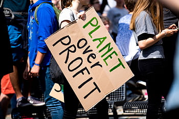 Youth climate protest with participants holding 'Planet Over Profit' sign. HD wallpaper