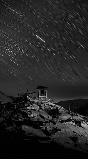 Black and white of star trails over a snow-covered mountain landscape at night. HD phone wallpaper
