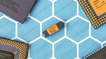 Close-up of various microprocessor chips on a blue hexagonal patterned surface, highlighting electronic technology. HD wallpaper