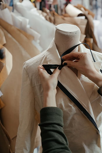 Close-up of tailor adjusting a garment on a mannequin, symbolizing fashion design in a creative studio. HD phone wallpaper