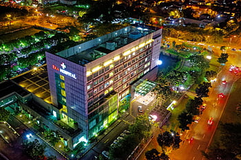 Stunning aerial view of Eka Hospital in Serpong, Indonesia, illuminated at night, capturing vibrant city lights and architecture. HD wallpaper